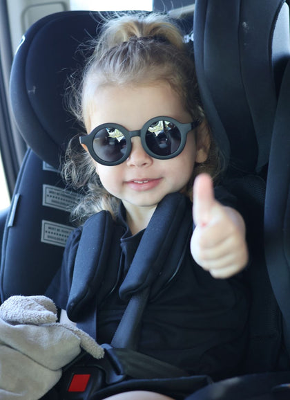 A child wearing Hey Peeps Roundabouts sunglasses in Matte Black