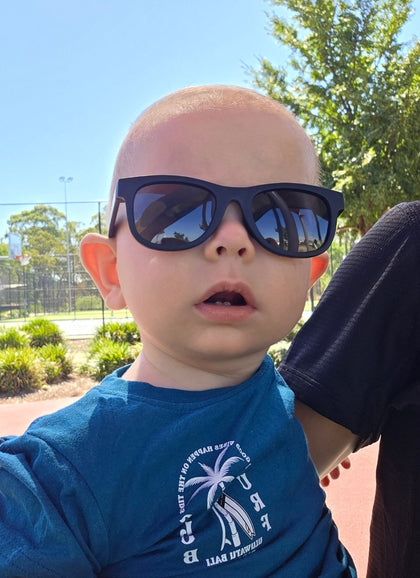 A child wearing Hey Peeps Little Legends sunglasses in Matte Black